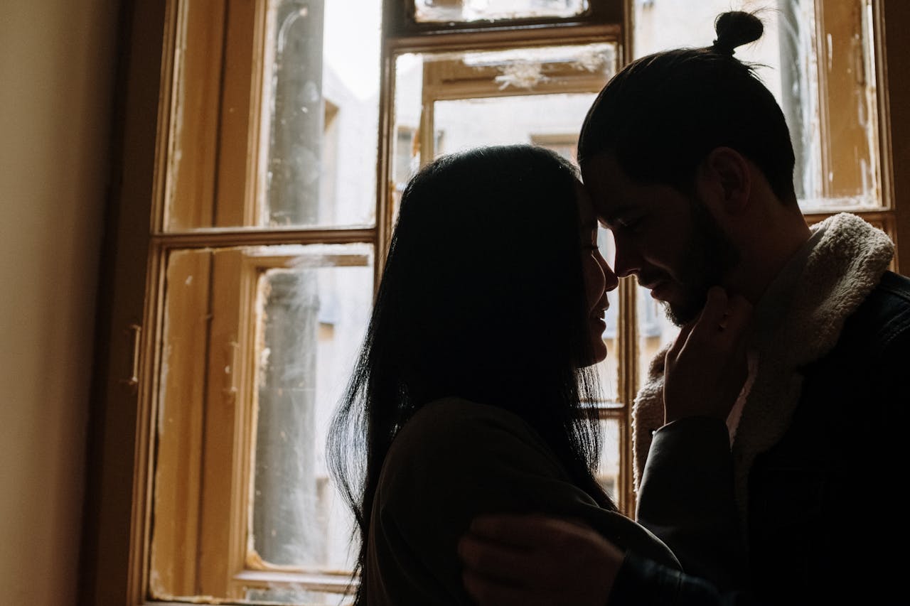 A couple sharing a tender intimate moment by a window