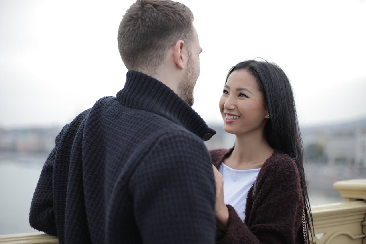 Joyful interracial couple embracing while sitting in a bright modern kitchen, smiling and enjoying the moment.
